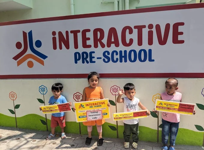 Children posing beside iNTERACTiVE Preschool signage