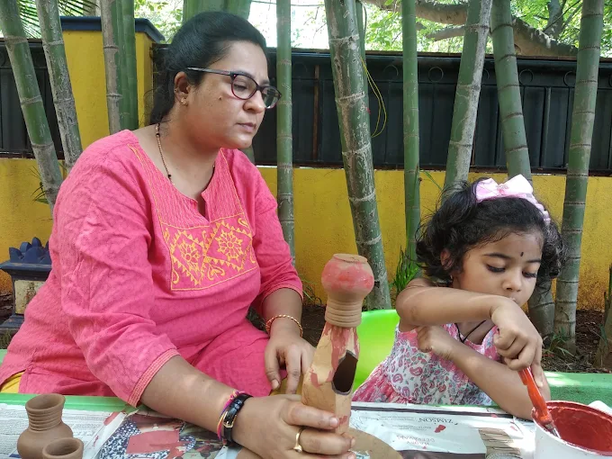 Child and teacher doing pottery craft outdoors