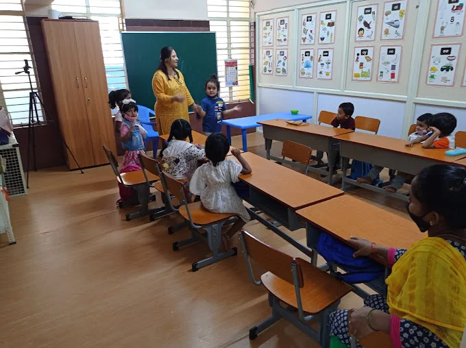 Teacher engaging children at classroom desks